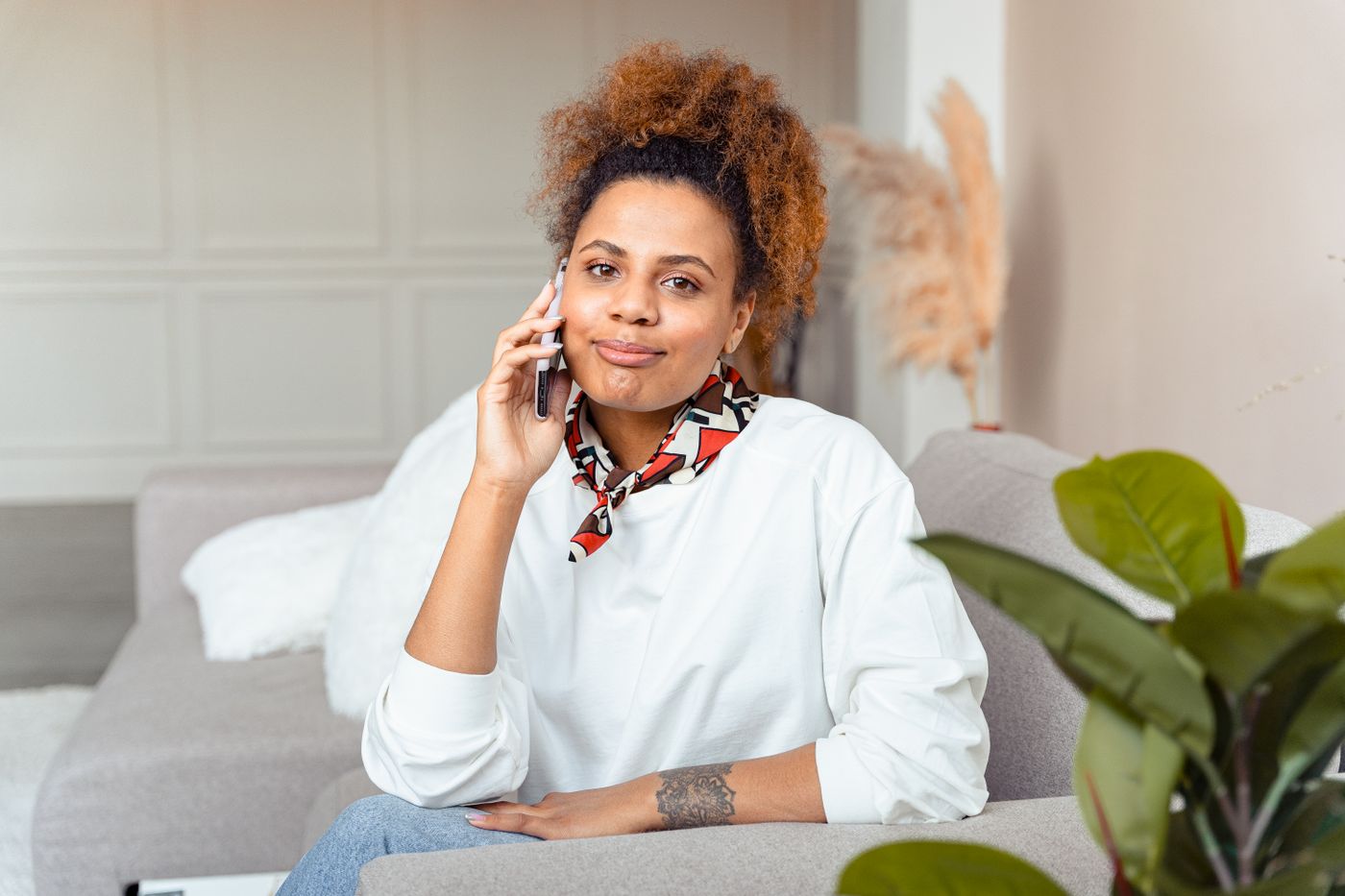 Mulher sorrindo enquanto agenda um atendimento pelo celular em casa