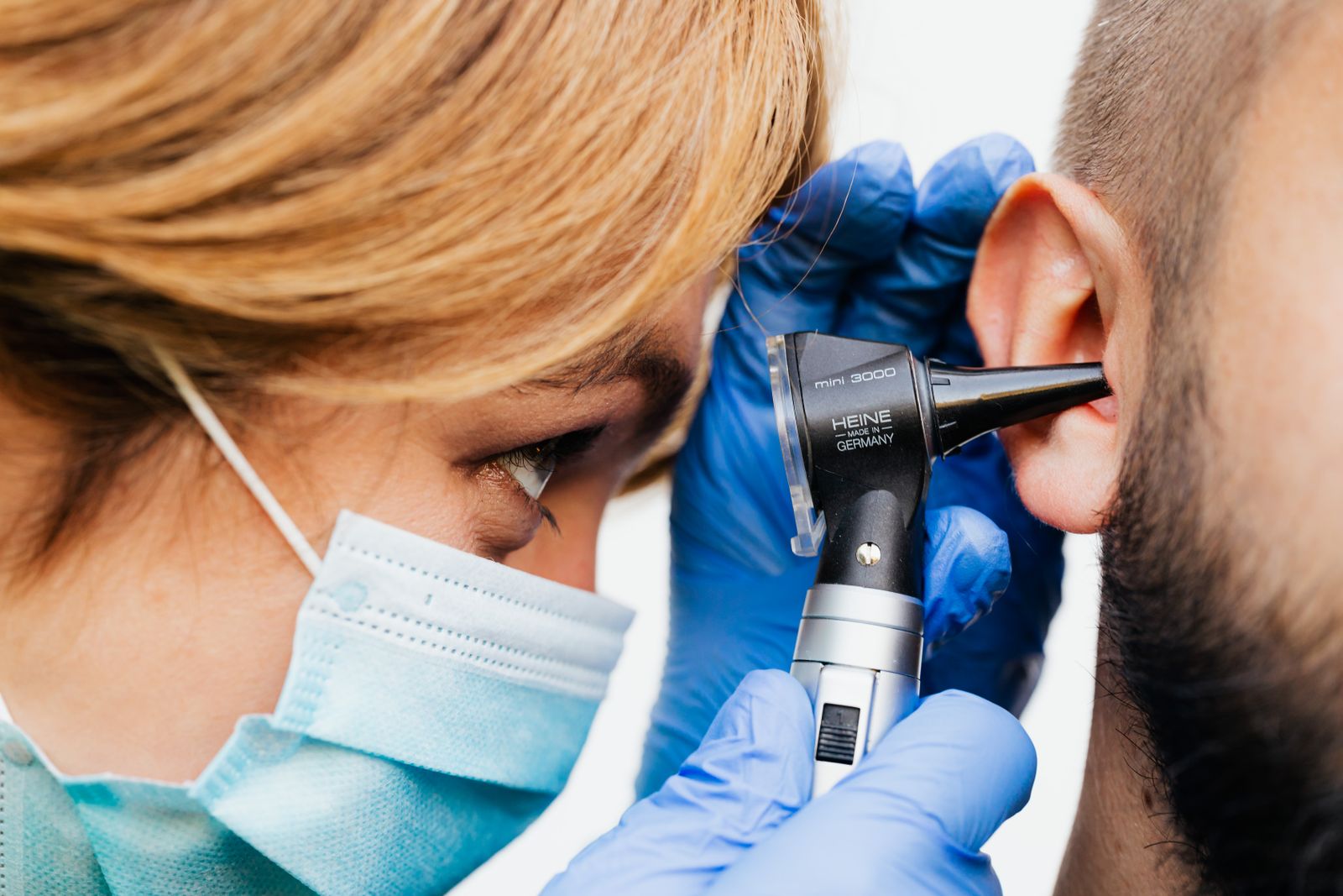 Médica examinando o ouvido de um paciente com otoscópio